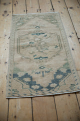 Distressed Oushak rug mat upper corner, muted teal and cream geometric patterns.