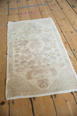 Angled view of a distressed Oushak rug showing its soft, even wear and faded floral pattern.