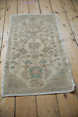 The worn pile of a distressed Oushak rug with muted seafoam green and beige floral details.