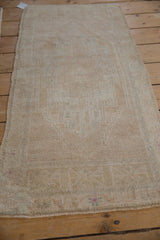 Distressed Oushak rug texture with antique ivory pile, even wear, and intact side selvage.