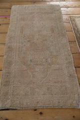 Distressed Oushak rug pile with even wear, featuring an intact side cord and subtle fuchsia and teal.