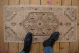 Distressed Oushak runner with faded ivory, blush, mint tones, shown with feet for scale.
