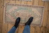 Distressed vintage Oushak rug with elongated medallion, stepped corners, pale blush, faded turquoise.