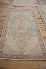 Distressed Oushak rug mat showing even pile wear, pale blush, faded turquoise, and intact side selvages.