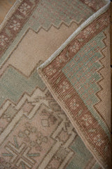 Folded Oushak rug showcasing distressed blush, turquoise pile, and hand-knotted back.