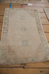 Faded teal geometric medallion on blush and ivory distressed Oushak rug with soft pile.