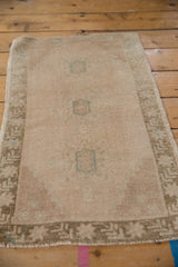 Low pile of distressed Oushak rug mat showing faded geometric medallions in antique ivory and teal.