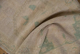 Distressed Oushak rug texture with visible knot heads and faded apricot and teal.