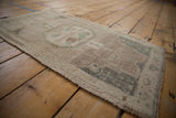 Distressed Oushak rug with even worn pile, intact side selvage, and muted colors.