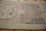 Distressed vintage Oushak rug with abrashed pile texture in beige and faded teal tones.