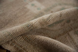 Distressed vintage rug pile, showing even wear to knot heads in beige and faded teal.
