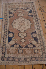 Vintage Oushak rug's central floral pinwheel motif in coffee brown and time-softened blue.