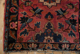 Vintage Lilihan rug corner: raspberry red field, navy floral border, and worn fringe.
