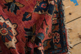 Meandering vine border with floral blossoms on vintage Lilihan rug, raspberry field, tattered fringe.