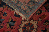Woven foundation and tattered fringe of a vintage Lilihan rug with raspberry floral pile.