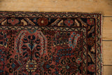 Vintage Lilihan rug corner showing intricate thousand flower bouquet in raspberry red and navy.
