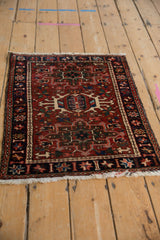 Vintage Karaja rug corner, brick red field, navy border with starburst floral blossoms, and fringe.