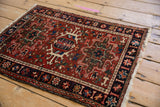 Karaja rug corner, navy border with starburst floral blossoms, brick red field, fringe.
