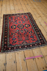 Vintage Lilihan rug with patterned border, red field, and navy serrated leaves, blossoms.