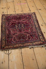 Corner of a vintage Sarouk rug showing worn fringe and detailed red floral patterns.