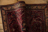 Intricate thousand flower design motif on the vintage Sarouk rug's cherry red field.