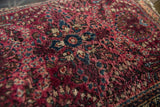 Vintage Sarouk rug's hand-knotted thousand flower motif in cherry red, navy, and ivory.