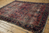 Worn cochineal red floral field and navy blue border of this vintage Lilihan rug.