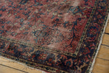 Tattered fringe, worn navy blue border, and cochineal field of a vintage Lilihan rug.