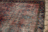 Vintage Lilihan rug's edge with tattered fringe, worn red pile, and navy border.