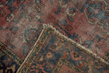 Worn raspberry red field, navy border, and tattered fringe of the vintage Lilihan rug.