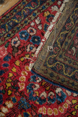 Vintage Sarouk rug's cherry red floral pile and hand-knotted reverse with tattered edge.