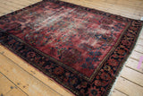 Vintage Lilihan rug corner detail, raspberry field with wear, navy floral border.