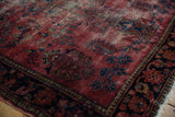 Vintage Persian Lilihan rug detail, showing raspberry red field, navy floral tendrils, and exposed foundation.