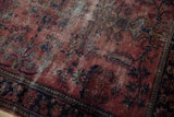 Vintage Lilihan rug with raspberry red field, deep blue floral vines, and visible foundation.