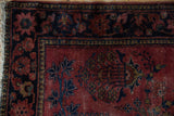 Vintage Lilihan rug close-up: raspberry field, navy blue floral blossoms, vines, and visible pile wear.