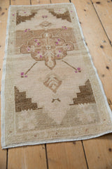 Distressed brown geometric motifs and small purple florets on vintage Oushak rug pile.