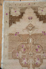 Close-up of distressed Oushak rug corner with intact selvage, even wear, and purple accents.