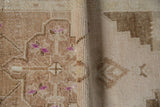 Textured pile and even wear on distressed Oushak rug, revealing side cord and beige motifs.