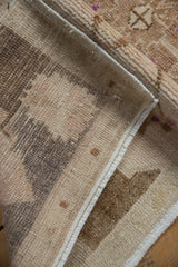 Vintage Oushak rug's hand-knotted foundation, restored side selvage, and worn beige and brown pile.