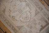 Distressed Oushak rug texture with worn pile, faded curvilinear beige and sand motifs.