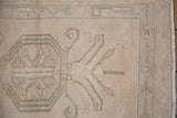Distressed ivory Oushak pile, showing even wear, dusty sage pattern, and intact fringe.