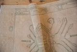 Distressed pile texture of a rolled vintage Oushak rug in antique ivory and dusty sage.