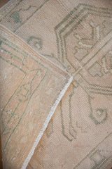 Distressed Oushak rug folded, revealing original side selvage and woven foundation.