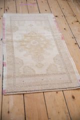 Distressed vintage Oushak rug's faded raspberry side selvage and even pile wear.