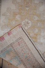 Vintage distressed Oushak rug corner folded, showing reverse weave, selvage, and foundation.