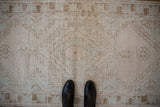 Distressed Oushak runner, faded cream and seafoam patterns, textured pile underfoot.