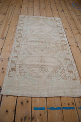 Distressed vintage Oushak runner with faded pattern and soft cream, seafoam, and bronze tones.