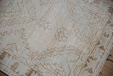 Distressed Oushak rug texture with cream, bronze, seafoam green patterns and mostly even wear.