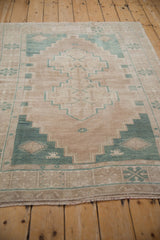 Distressed wool pile shows stepped celadon green geometric patterns on beige.
