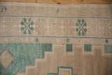 Distressed Oushak rug detail showing camel, celadon green geometric patterns and weaver's knot.